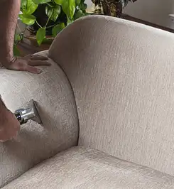 Professional upholstery cleaner deep-cleaning a fabric sofa with a handheld extraction tool and hose Madison, WI.